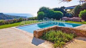 A swimming pool with a stone border, surrounded by greenery and a view of the sea. - Exclusive villa with private pool (Santa Reparata)
