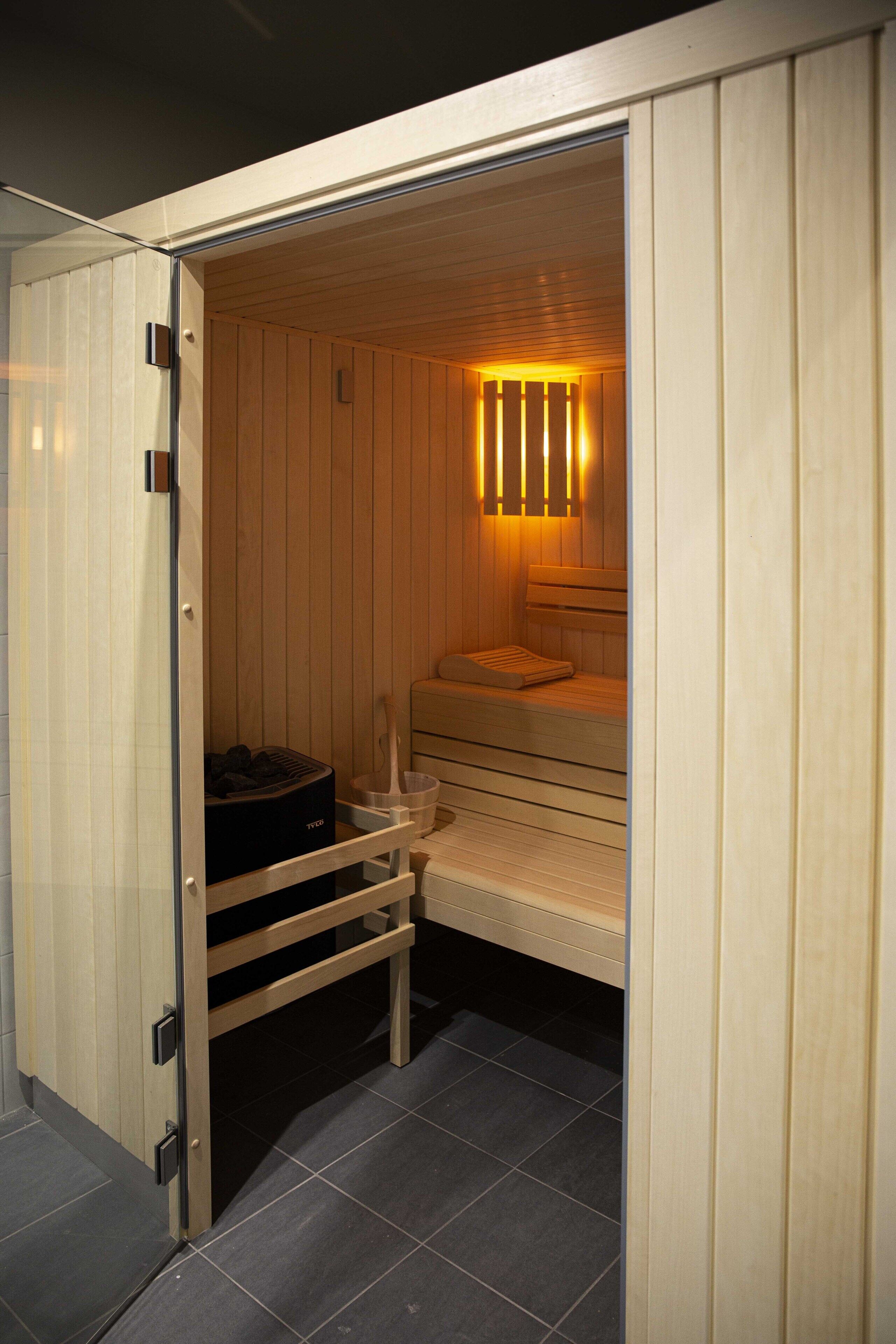A sauna with a bench, a wooden bench, and a towel rack.