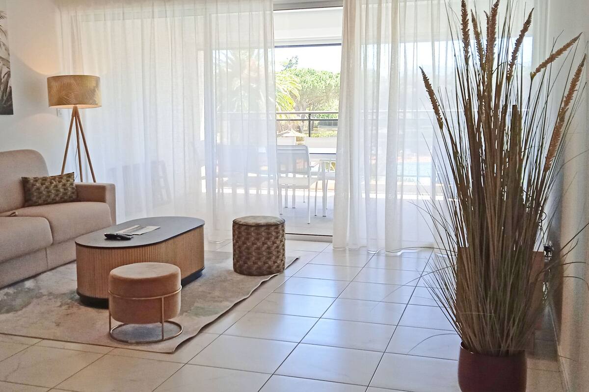 A living room with a sofa, coffee table, lamp, and a potted plant.