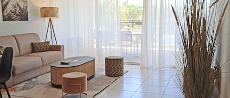 Un salon avec un canapé, une table basse, une lampe et une plante en pot.