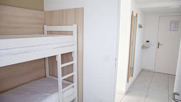 A bunk bed room with a wooden headboard, a white door with a sign, and a tiled floor.