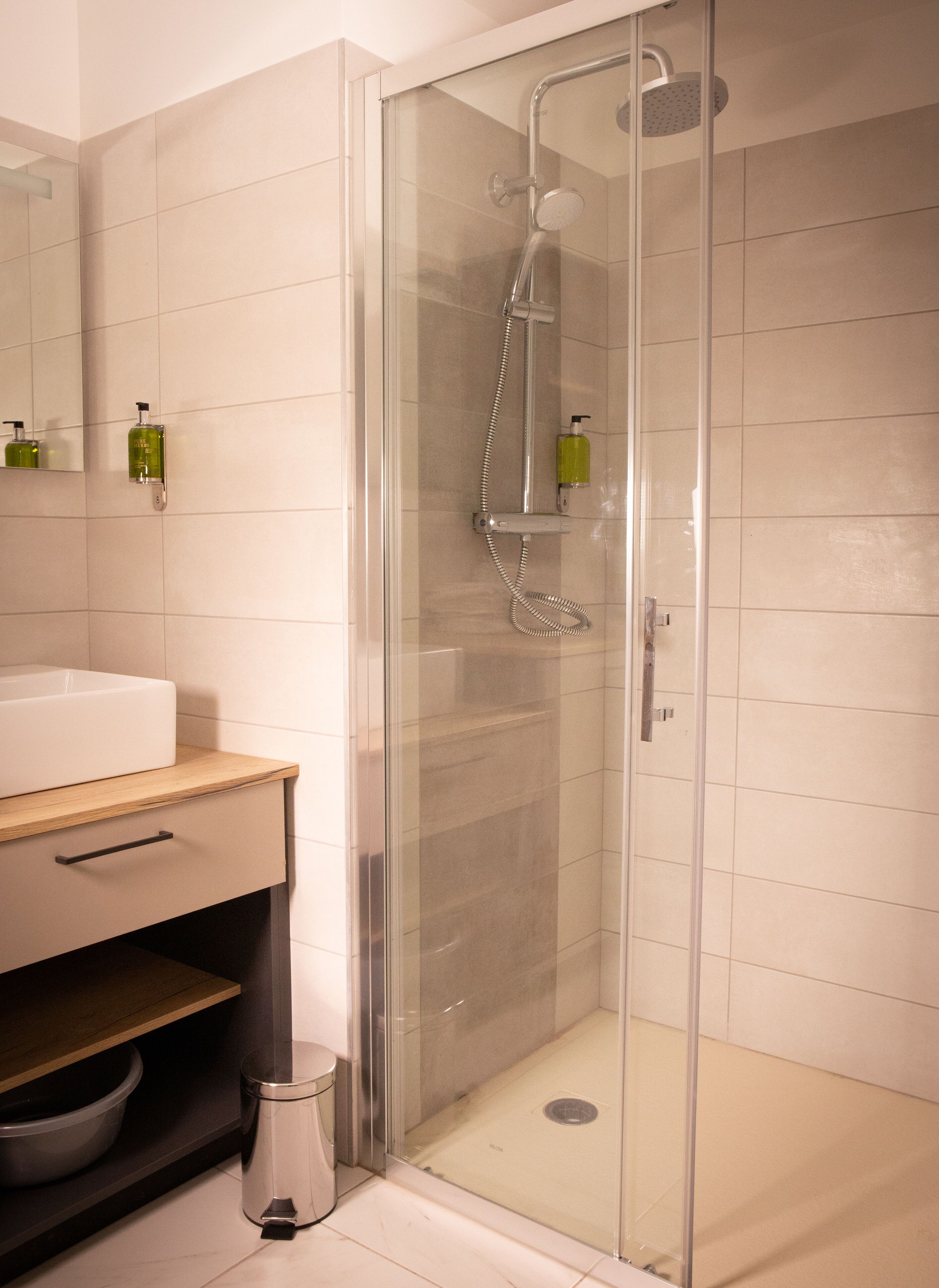 A modern bathroom with a glass-enclosed shower, a white sink, and a mirror.