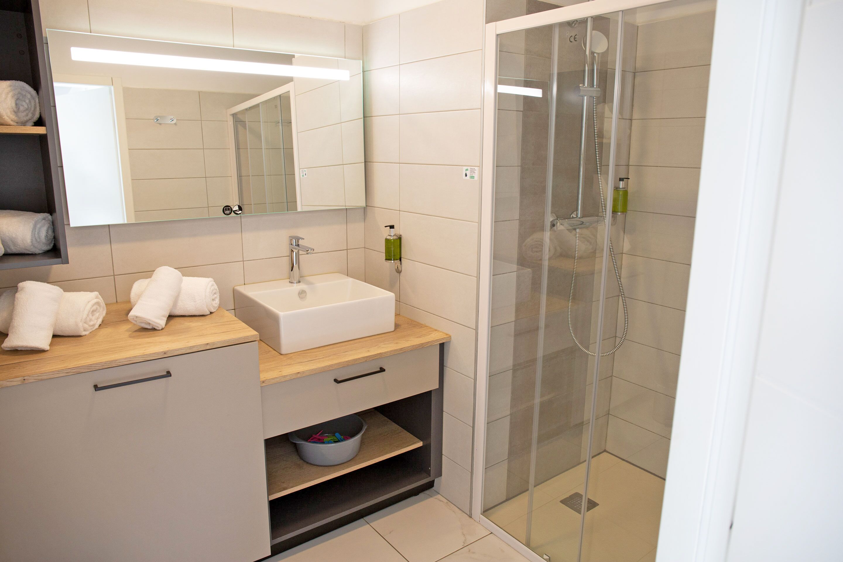 A modern bathroom with a sink, mirror, and glass-enclosed shower.