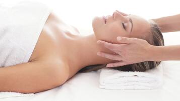 A person lying on a bed with a white towel covering their upper body.