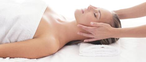 A person lying on a bed with a white towel covering their upper body.