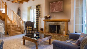 A living room with a fireplace, a sofa, a coffee table, and a staircase.