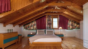 A bedroom with a wooden ceiling, a bed, a nightstand, a dresser, and a window with curtains.