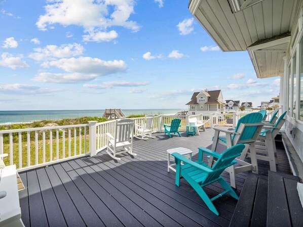 A wooden deck with outdoor seating and a view of the ocean.
