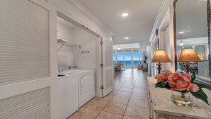 A hotel corridor with a laundry area, a dining area with a view, and a table with a lamp and flowers. - New to the Rental Market, Lazy River and Slide, Beachfront!! (Orange Beach)