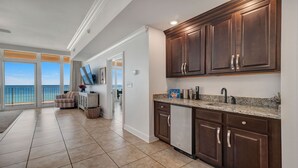 A modern kitchen with dark wood cabinets, a granite countertop, and a built-in dishwasher. - New to the Rental Market, Lazy River and Slide, Beachfront!! (Orange Beach)