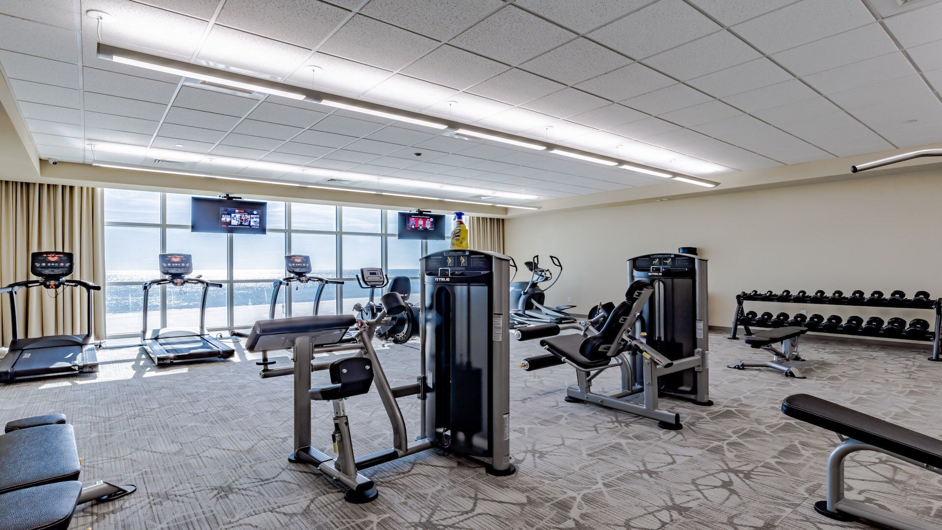 A gym with treadmills, weight machines, and a rowing machine.