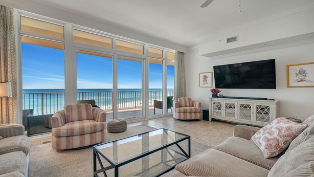 A spacious living room with a large TV, comfortable seating, and a balcony with a view of the ocean. - New to the Rental Market, Lazy River and Slide, Beachfront!! (Orange Beach)