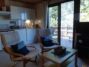 A cozy living area with two cushioned chairs, a coffee table, and a view of the outdoors through a sliding glass door. - Gîte l'Ancolie in Céuze (MANTEYER)