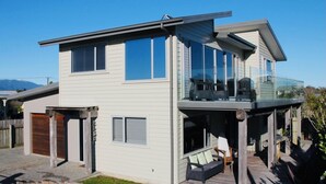 Een modern huis met twee verdiepingen, een balkon, grote ramen en een terras.