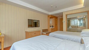 A hotel room with two beds, a TV, a wooden cabinet, and a bathroom visible through a glass door. - Vienna 3 Best Hotel (Guangzhou)