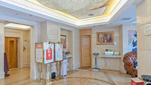 A hotel lobby with a chandelier, a reception desk, and a plush armchair. - Vienna 3 Best Hotel (Guangzhou)