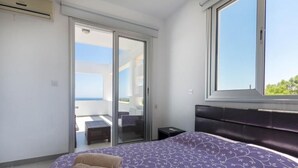 Une chambre avec un lit, une fenêtre et une porte-fenêtre coulissante donnant sur un espace extérieur.