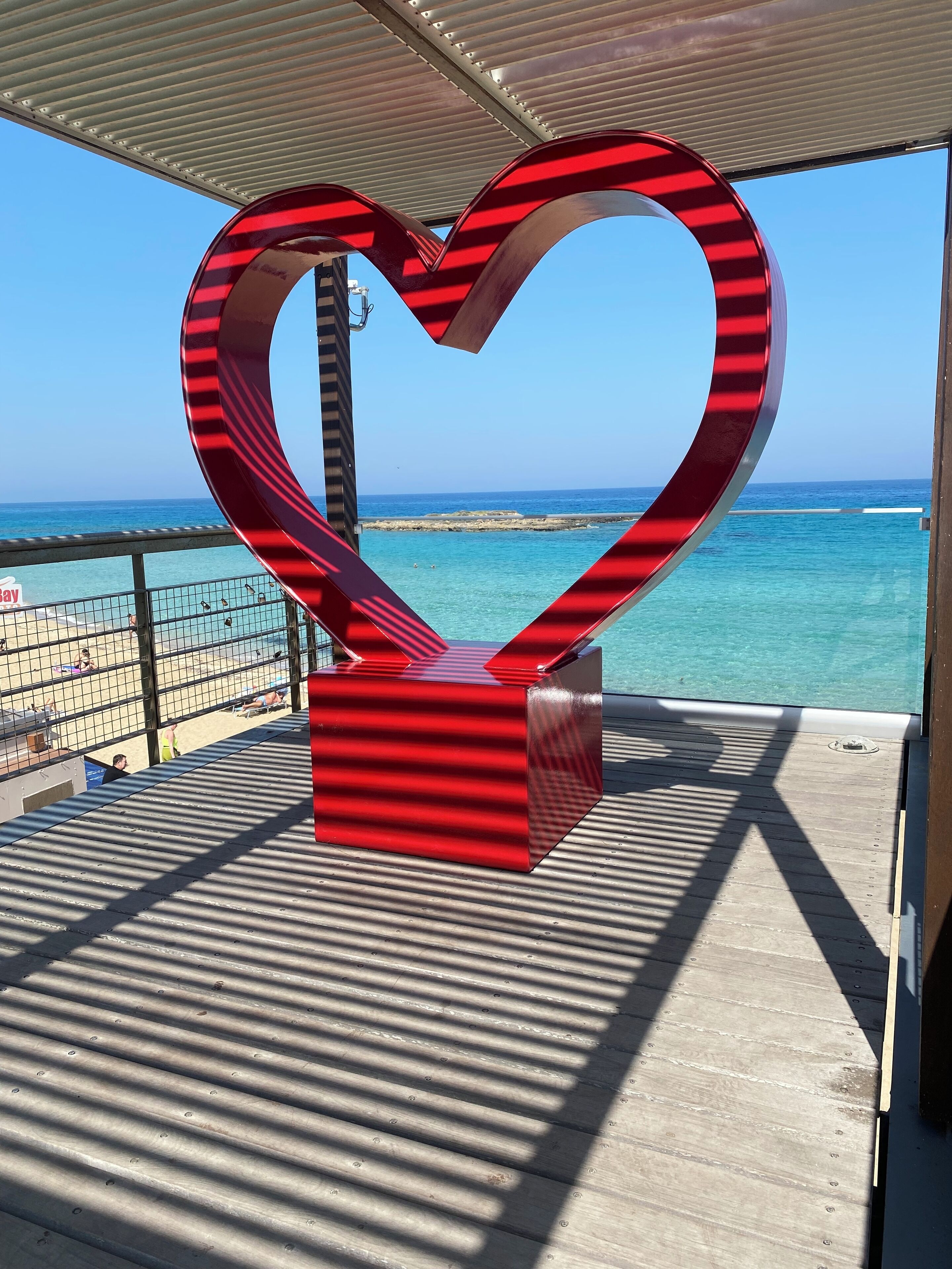 Een hartvormige sculptuur op een houten terras met uitzicht op de oceaan.