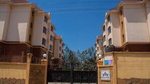 A gated residential complex with multiple apartment buildings, a clear sky, and a sign indicating a medical facility. - Lilly's Furnished Apartments (Nakuru)