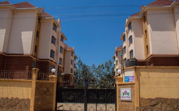 A gated residential complex with multiple apartment buildings, a clear sky, and a sign indicating a medical facility.