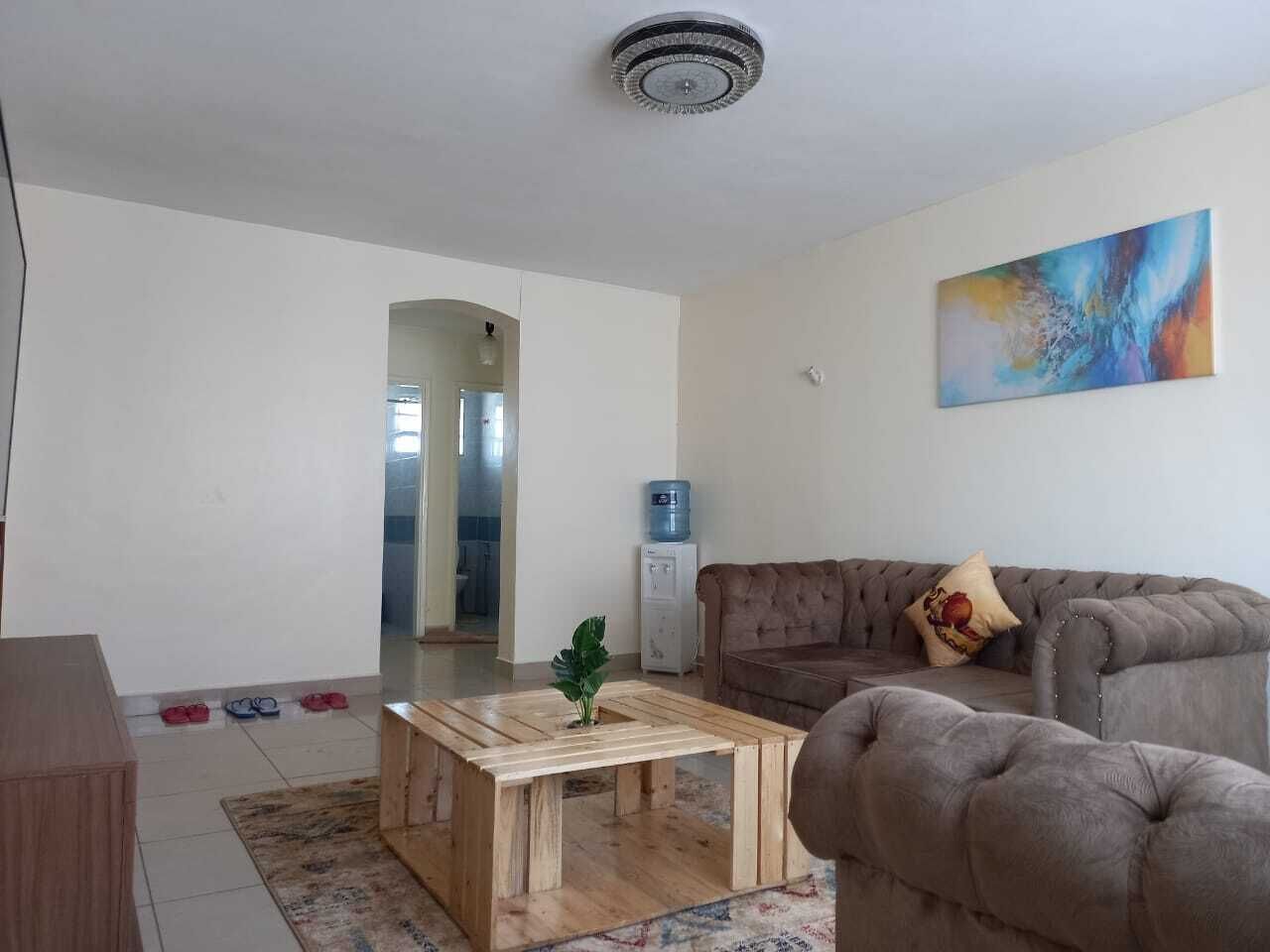 A living room with a sofa, a coffee table, and a water dispenser.
