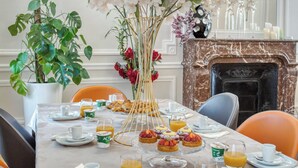 Une table à manger dressée avec des assiettes, des verres et un centre de table composé de fleurs blanches.