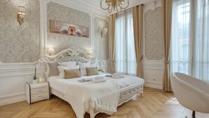 Une chambre à coucher luxueuse, dotée d’un grand lit, d’une coiffeuse et d’un fauteuil moderne.