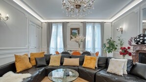 Un salon moderne avec un canapé en cuir noir, une table basse en verre et un lustre.