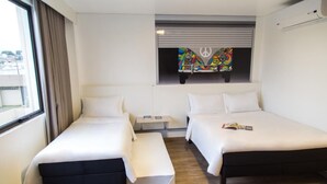 Una habitación de hotel con dos camas, una mesita y una ventana con cortinas.