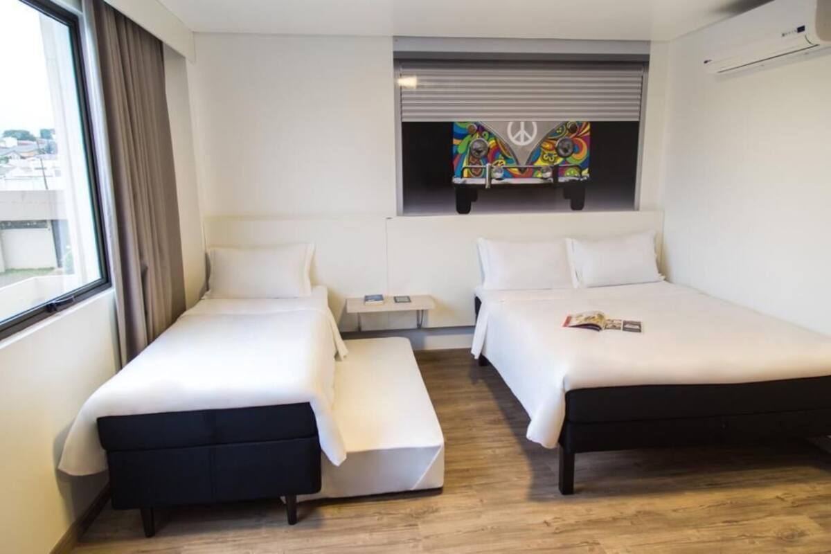 Una habitación de hotel con dos camas, una mesita y una ventana con cortinas.