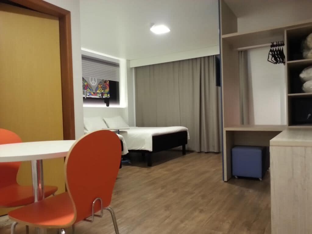 A compact hotel room with a bed, a small table, and a chair.
