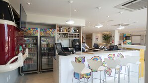 Zona de bar moderna con barra, asientos y nevera llena de bebidas.