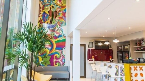 Un interior moderno con un mural colorido, zona de estar y bar.