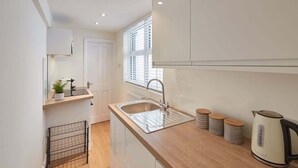 Una cocina moderna con encimera de madera, pileta de acero inoxidable y armarios blancos.