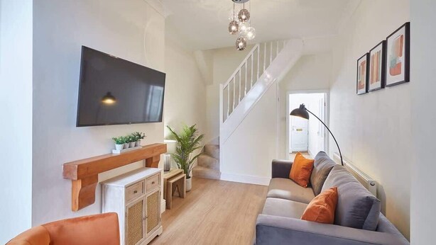 Una sala de estar moderna con un televisor de pantalla plana, estanterías de madera, un sofá y una escalera.