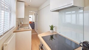 Una cocina moderna con estufa integrada, un lavamanos y una ventana con persianas.