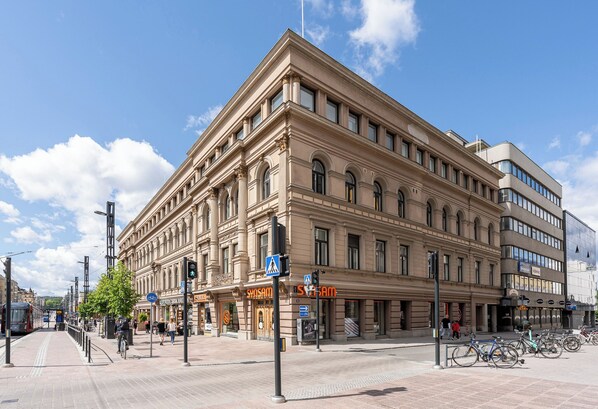 A large, historic building with multiple floors, a prominent entrance, and a bicycle parking area. - Renovated Loft in a Historical Downtown Building (Tampere)