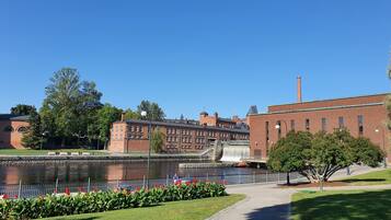 A riverside walkway with a brick building, a bridge, and a water tower in the background.