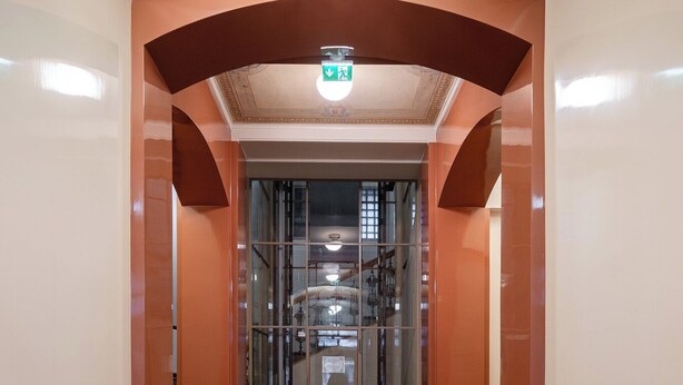 A hallway with a glass elevator, a patterned floor, and a decorative ceiling. - Renovated Loft in a Historical Downtown Building (Tampere)
