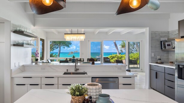 A modern kitchen with a large island, a view of the ocean, and a chandelier.