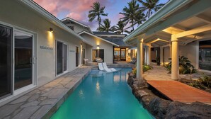 A pool area with a clear view of the pool, lounge chairs, and a wooden deck.