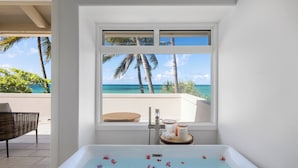 A bathroom with a bathtub, a window with a view of the ocean, and a towel rack.