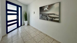 A hallway with a blue-framed door, a potted plant, and a framed picture on the wall. - Santorini In Puerto Rico Inc. Since 2017... (Río Grande)