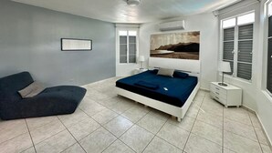 A modern bedroom with a large bed, a sofa, and a window with shutters. - Santorini In Puerto Rico Inc. Since 2017... (Río Grande)
