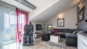 Ett modernt vardagsrum med en soffa i läder, en massagestol, en tv och en bokhylla.