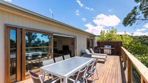 A deck with a dining table and chairs, a grill, and a view of the surrounding landscape. - Strathlea (Lorne)