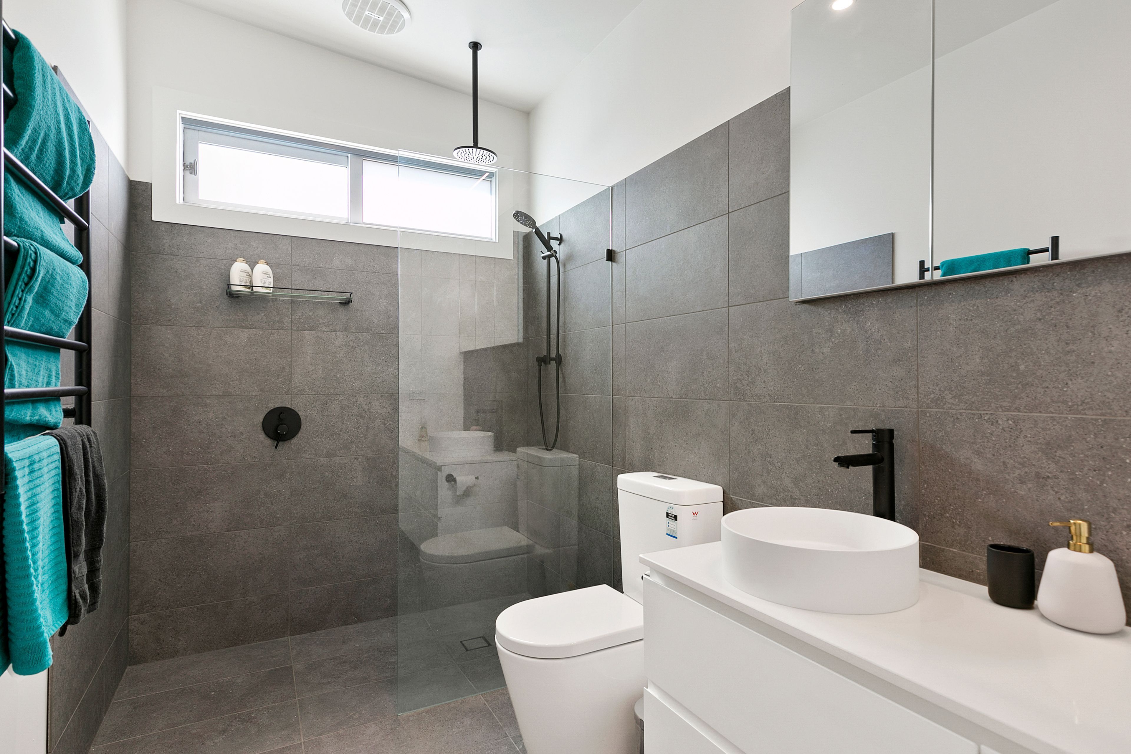 A modern bathroom with a shower, toilet, and sink.