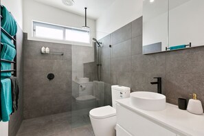 A modern bathroom with a shower, toilet, and sink. - Strathlea (Lorne)