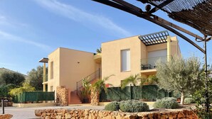 Une maison moderne à deux étages, dotée d’un mur de soutènement en pierre, d’un escalier et d’un espace patio.