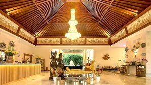 A lobby with a wooden ceiling, a chandelier, a reception desk, and a sofa. - New Sunari Lovina Beach Resort (Buleleng)